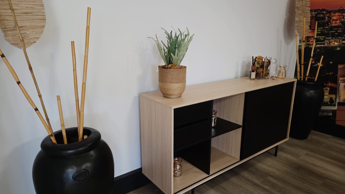 Completed office styling detail with timber console, black storage fronts, ceramics, and greenery